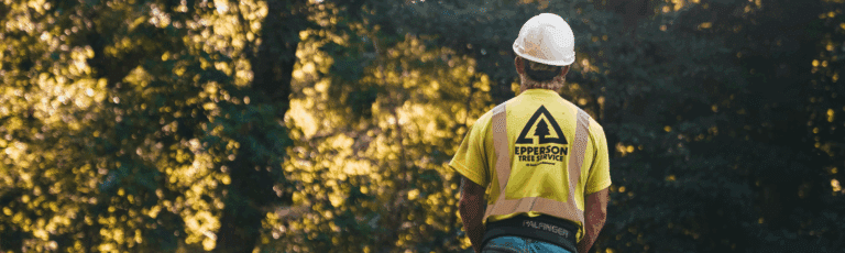 A man in a yellow shirt and hat stands on a trail, surrounded by greenery, promoting environmental awareness using environmental services specifc content.