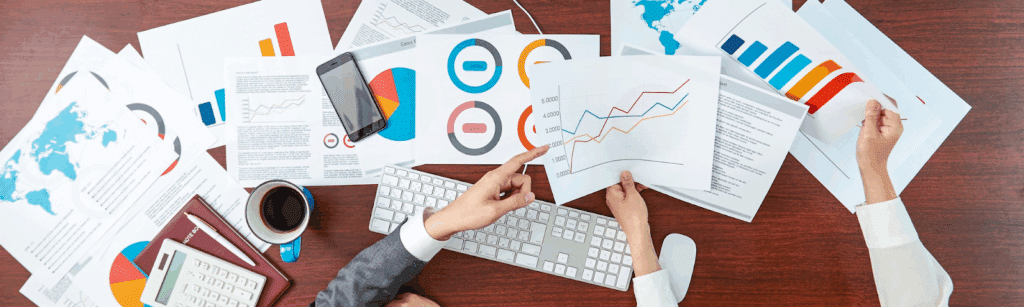Business professionals analyzing graphs and papers on a computer, focusing on social media brand growth strategies.