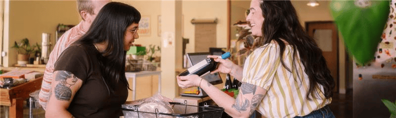 Two women standing in front of a table with a bottle of wine on it, showing a friendly social scene representing local SEO foot traffic.
